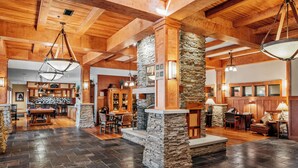A spacious lobby with a stone fireplace, wooden beams, and a bar area. - Tamarack Lodge of Traverse City (Traverse City)