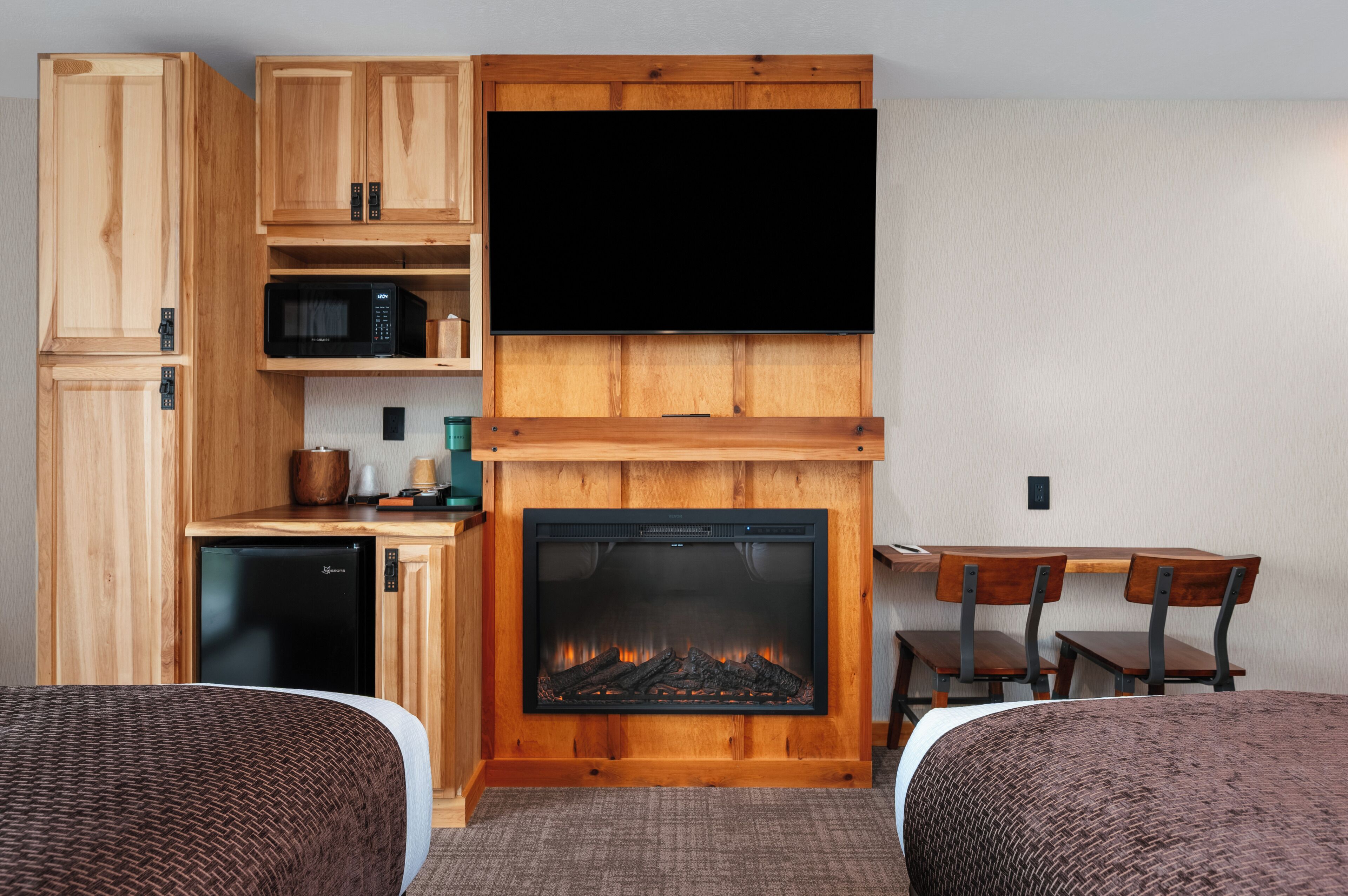 A room with a fireplace, wooden cabinets, a television, and a dining area.