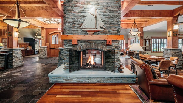 A spacious living area with a stone fireplace, leather seating, and a large dining table. - Tamarack Lodge of Traverse City (Traverse City)