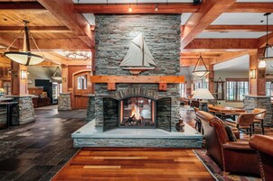 Un amplio salón con chimenea de piedra, asientos de cuero y una gran mesa de comedor.