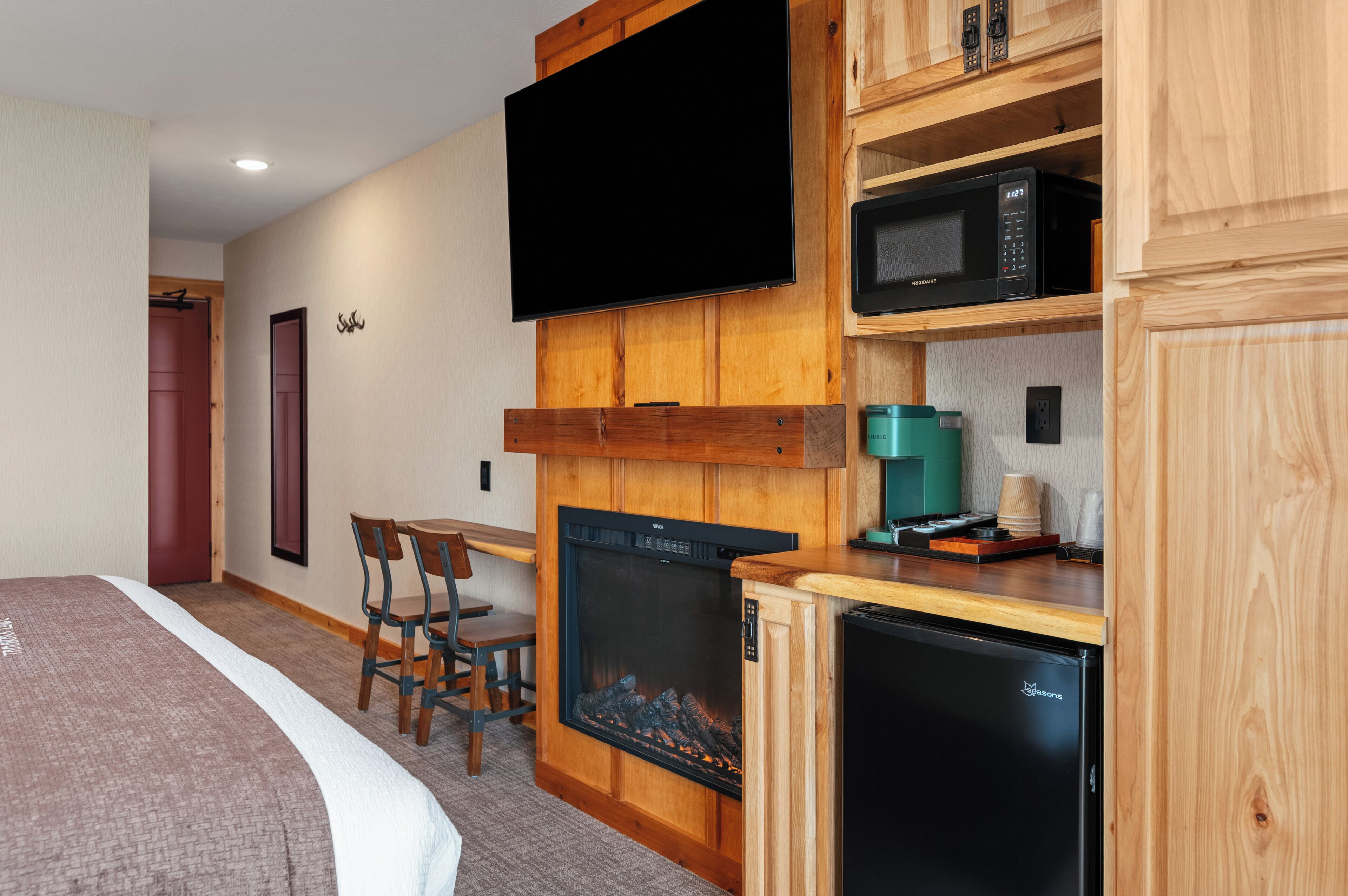 A room with a bed, a fireplace, a television, a microwave, and a small refrigerator.