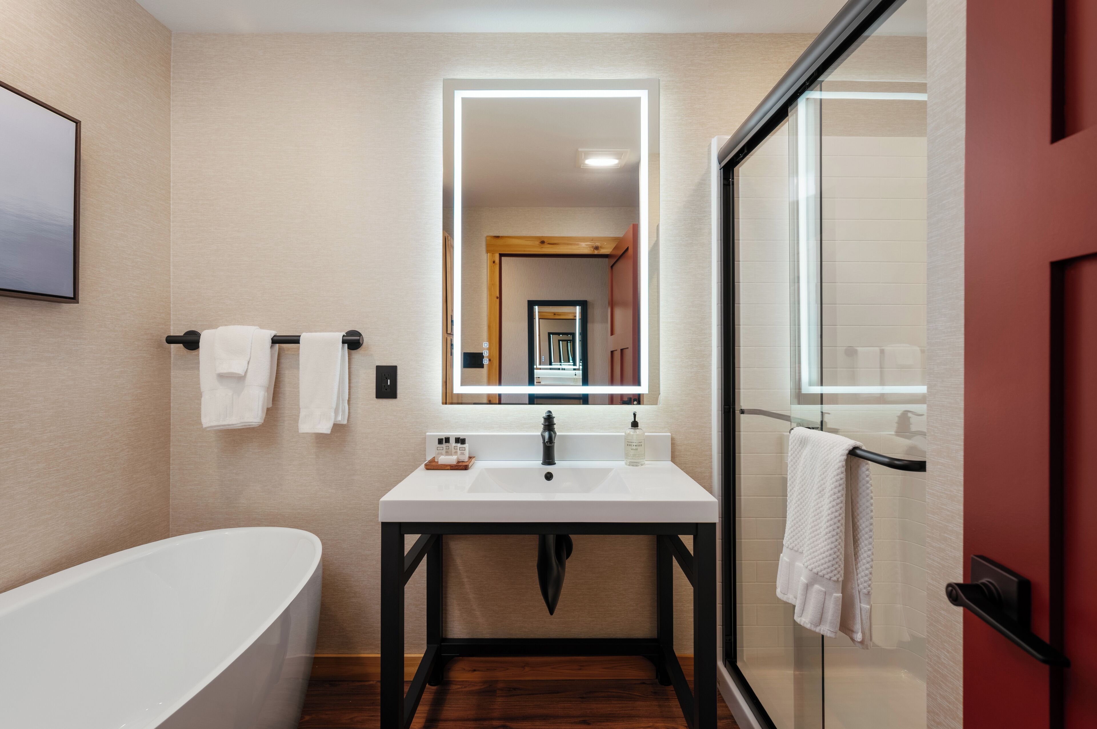 A modern bathroom with a freestanding bathtub, a white sink with a mirror above it, and a glass shower enclosure.