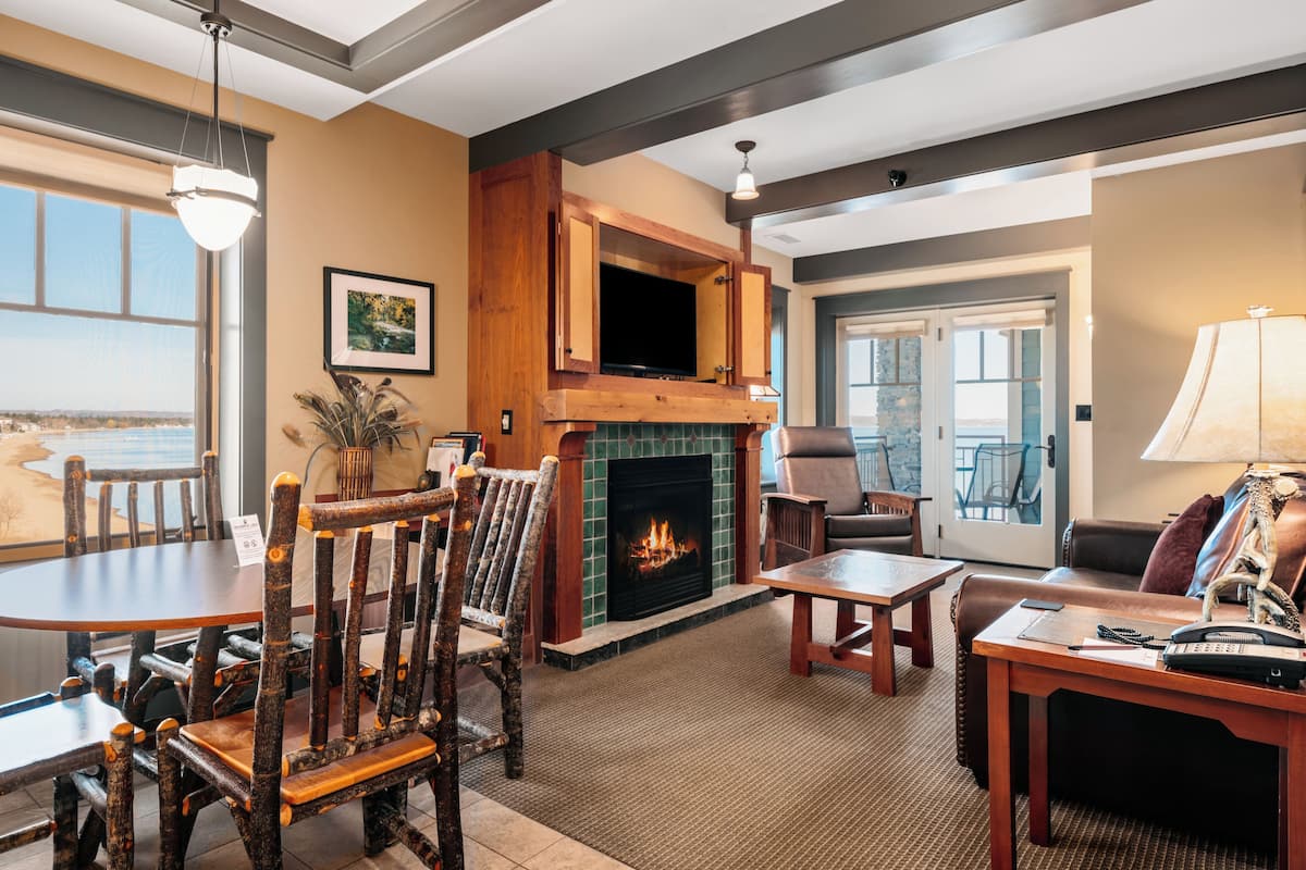 A cozy living room with a fireplace, wooden furniture, and a view of the outdoors.