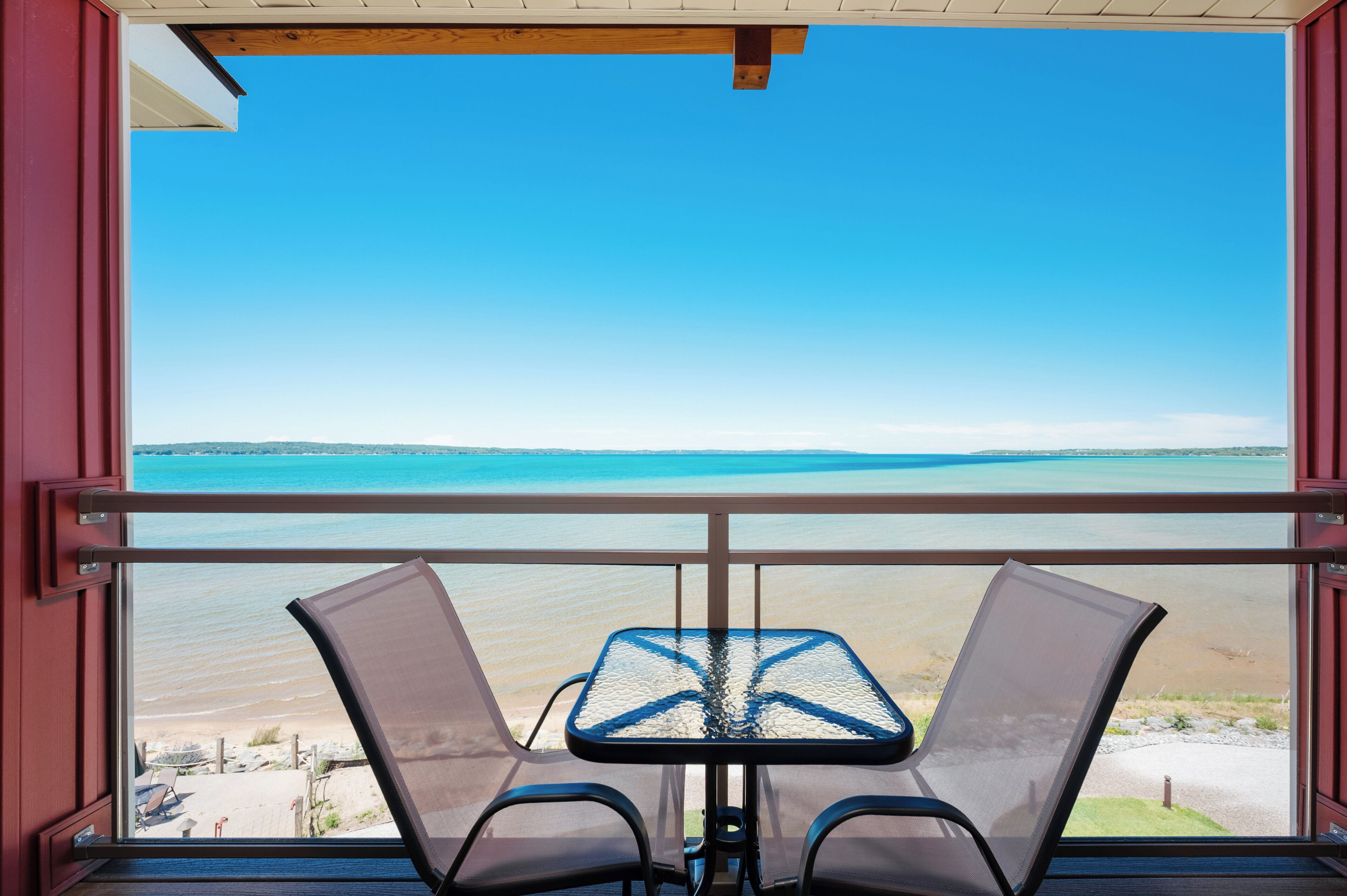 Un balcón con una mesa y dos sillas, con vistas a una playa y el océano.