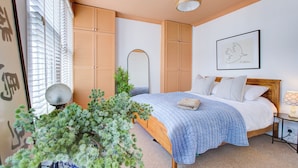 A bedroom with a wooden bed, a large mirror, and a framed artwork on the wall. - Cosy house on the seafront - Pass the Keys (Southend-on-Sea)