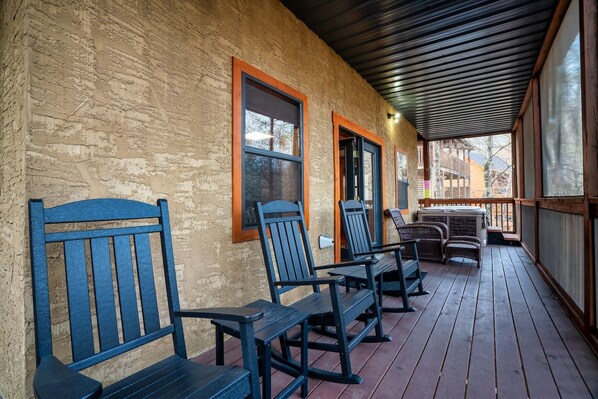 A covered porch with wooden benches and a hot tub.