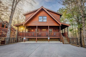 A log cabin with a front porch, a staircase, and a sign indicating a power outlet.