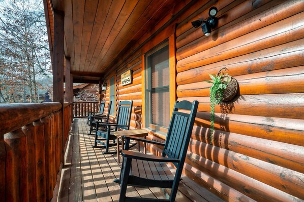A wooden cabin with a porch, outdoor seating, and a decorative wreath. - 3 Min to Parkway | Private Resort Pool | Top 5%! (Pigeon Forge)