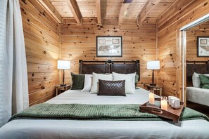 A wooden-paneled bedroom with a bed, two bedside tables, lamps, and a mirror.