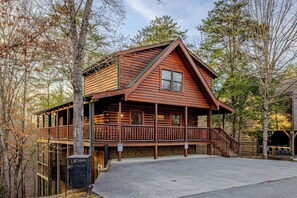 A log cabin with a porch, a staircase, and a stone wall. - 3 Min to Parkway | Private Resort Pool | Top 5%! (Pigeon Forge)