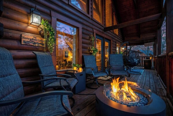 A log cabin with a fire pit, outdoor seating, and a sign reading 'The Honey Bear Lodge.'