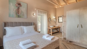 Une chambre bien éclairée, avec un grand lit, une table de chevet sur laquelle se trouvent un bol et un miroir, et une armoire.