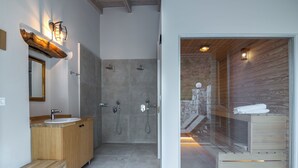Une salle de bain moderne avec un meuble-lavabo en bois, une douche à l’italienne avec des parois en verre et un porte-serviettes apparent.
