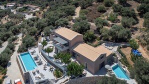 Vue aérienne d’une villa moderne dotée d’une piscine, de murs en pierre et d’un jardin.