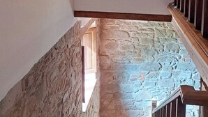 Una escalera con paredes de piedra y barandillas de madera que conduce a un piso superior.