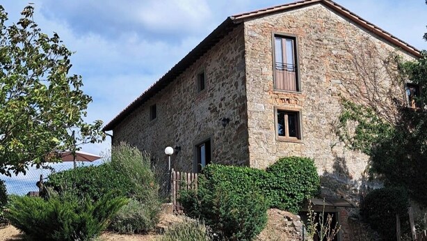 Un edificio de piedra con techo inclinado, una puerta de madera y una ventana pequeña.