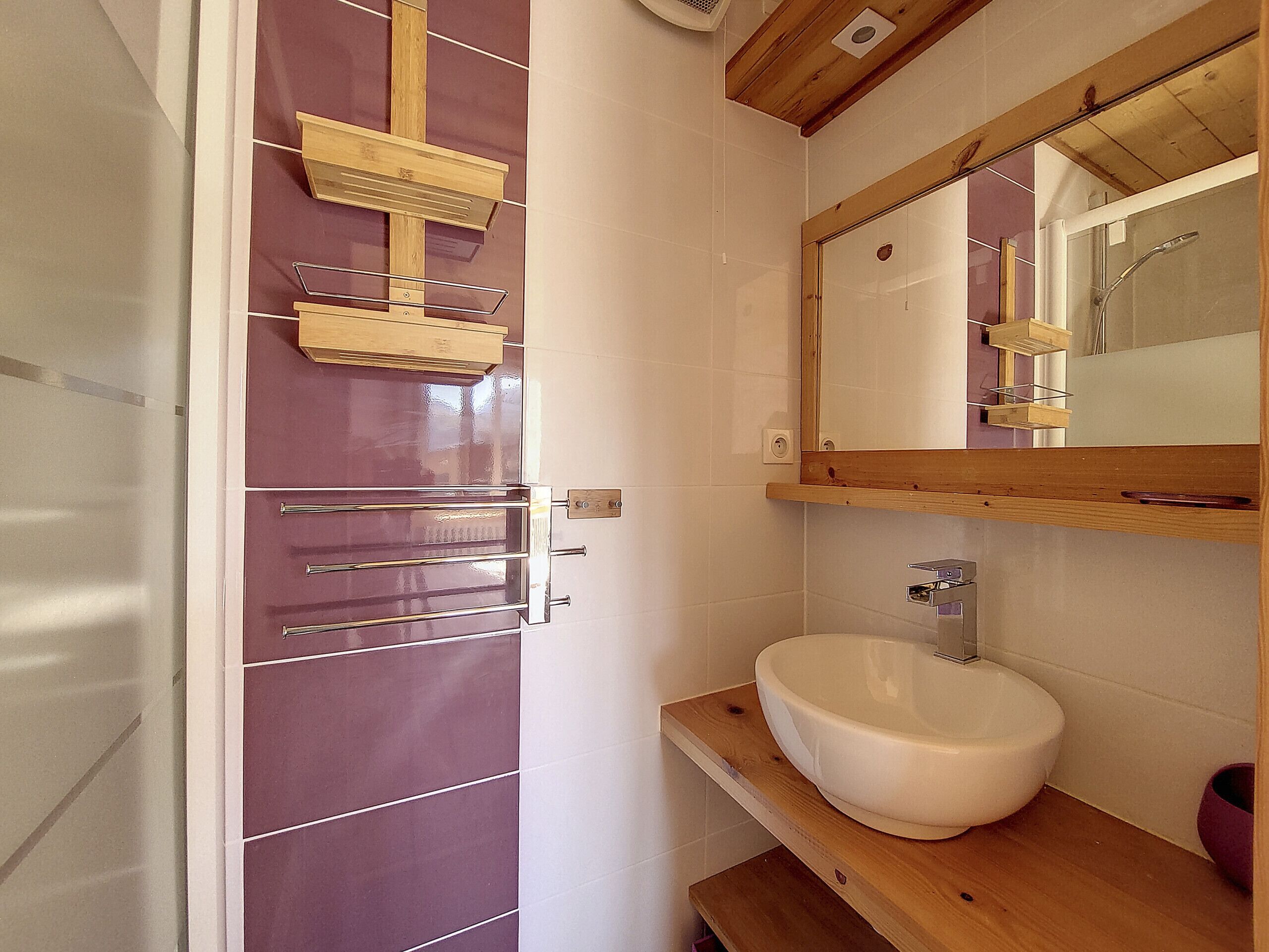 A bathroom with a wooden vanity, a white sink, and a mirror above the sink.