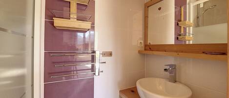 A bathroom with a wooden vanity, a white sink, and a mirror above the sink.