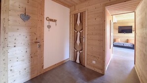 A wooden interior with a 'Chalet' sign, a heart-shaped decoration, and a television in a room with a bed.