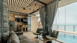 A modern living room with a sofa, armchairs, and a small table with a laptop. A large window offers a view of the ocean. - Sea&Sky luxury absolute beachfront villa (Koh Samui)