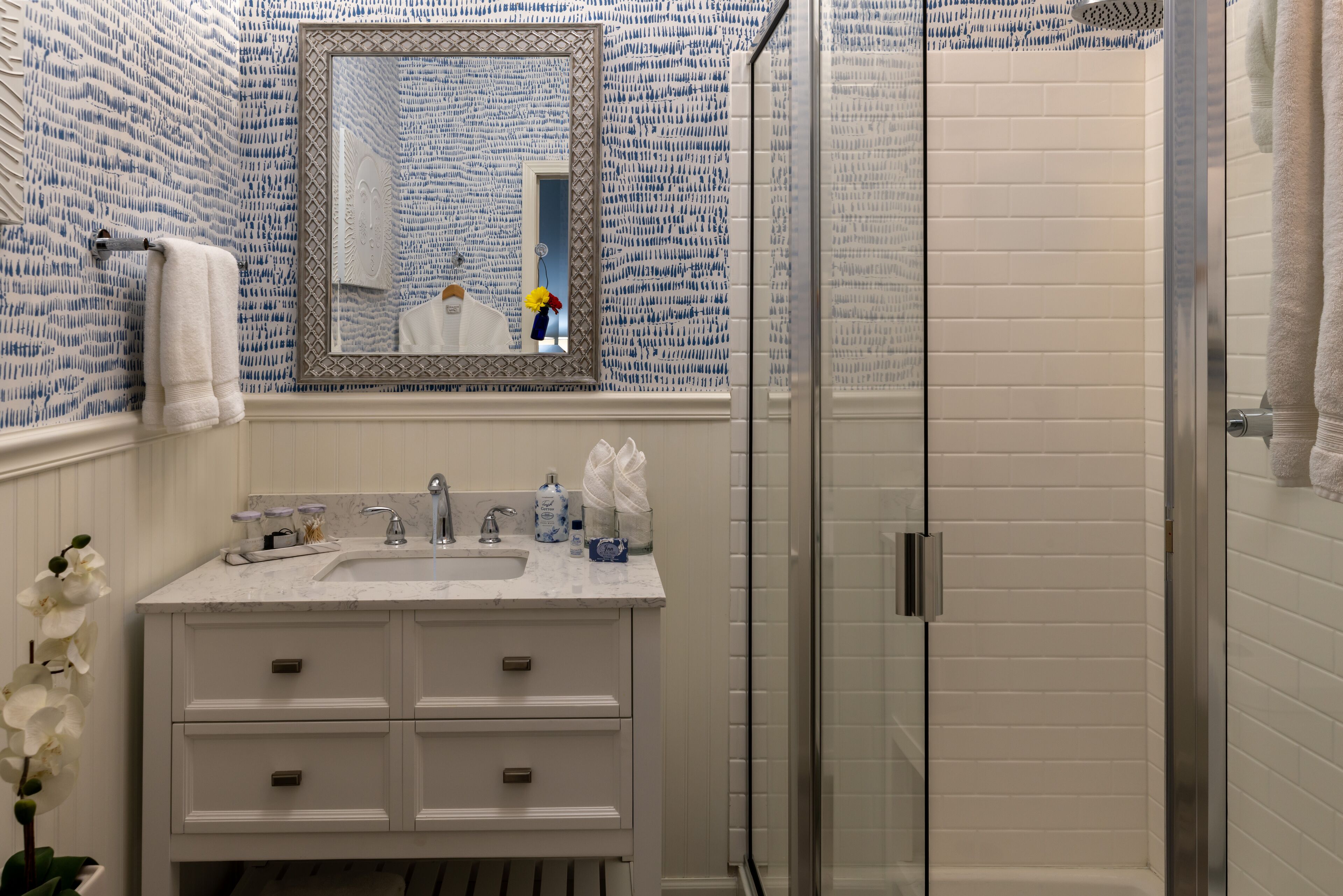 A bathroom with a white sink, mirror, and glass shower enclosure.