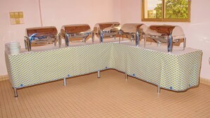 Ein langer, gebogener Büfettisch mit gemustertem Tischläufer und Metallgestell.