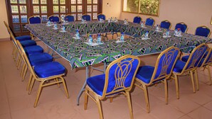 Ein Konferenzraum mit einem langen Tisch, blauen Stühlen und einer gemusterten Tischdecke.