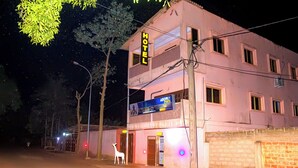 Ein zweistöckiges Gebäude mit einem 'HOTEL'-Schild, einem 'BOMBY'-Schild und einer 'BOMBY'-Werbeanzeige.