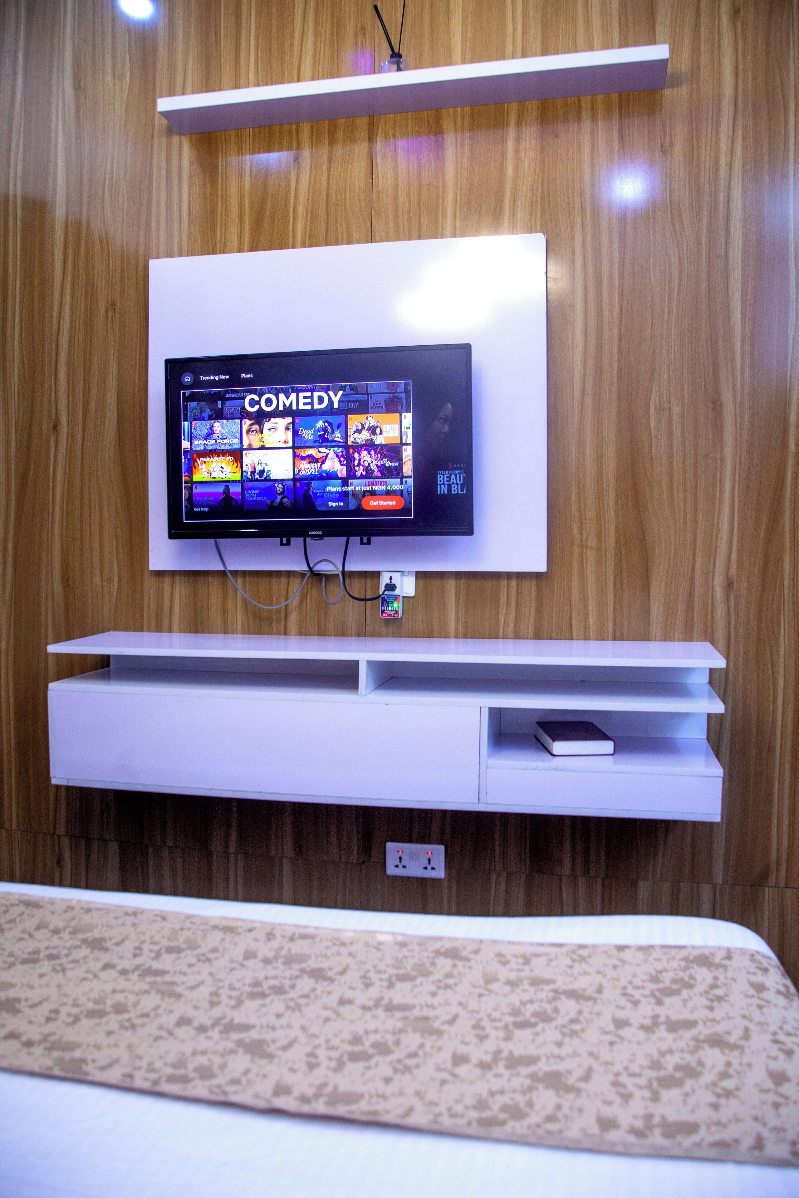 Un televisor de pantalla plana montado en una pared de madera, con un mueble bajo para entretenimiento en color blanco.