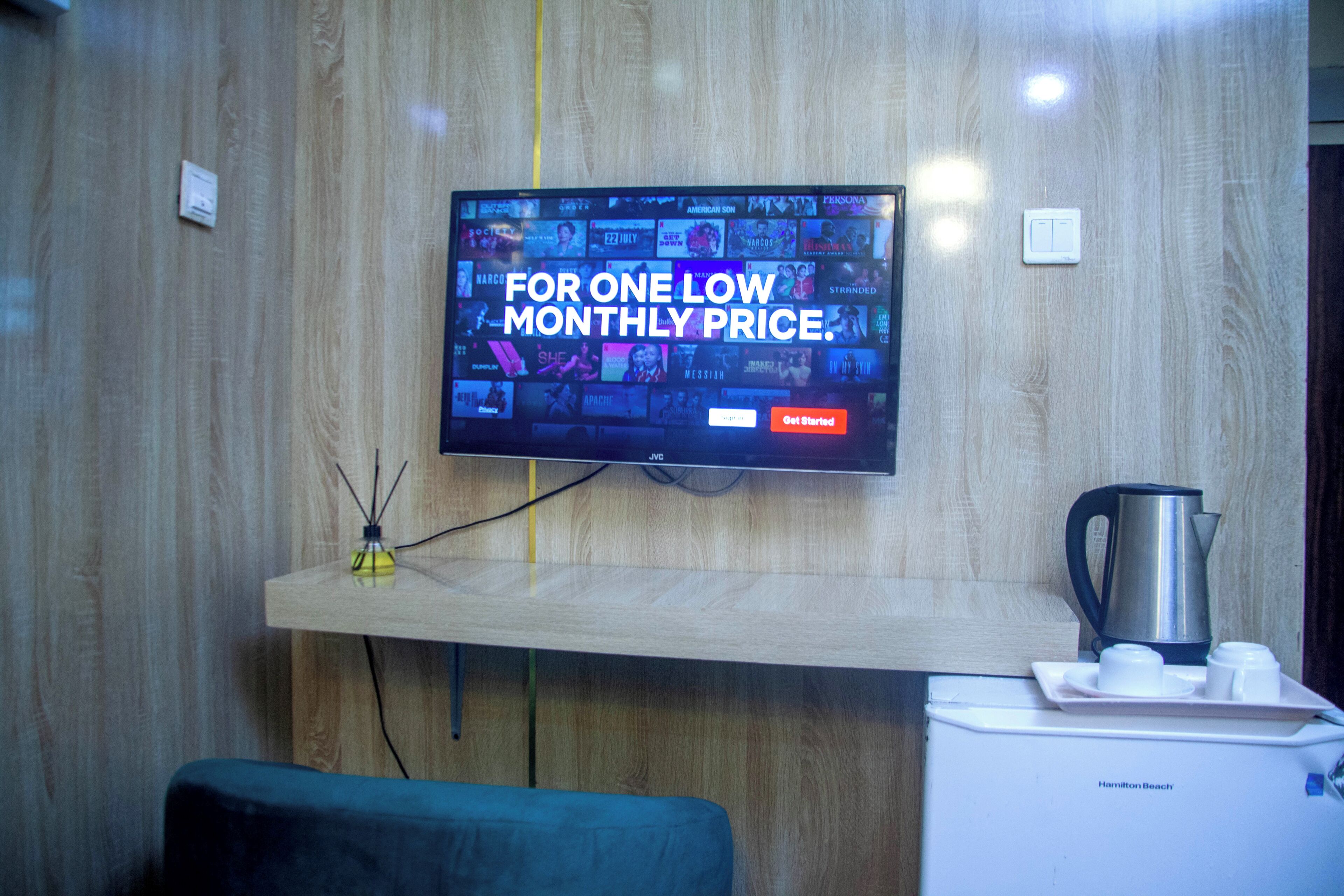 Een flatscreen-tv bevestigd aan een houten muur, waarop een advertentie voor een maandelijks abonnement wordt getoond.