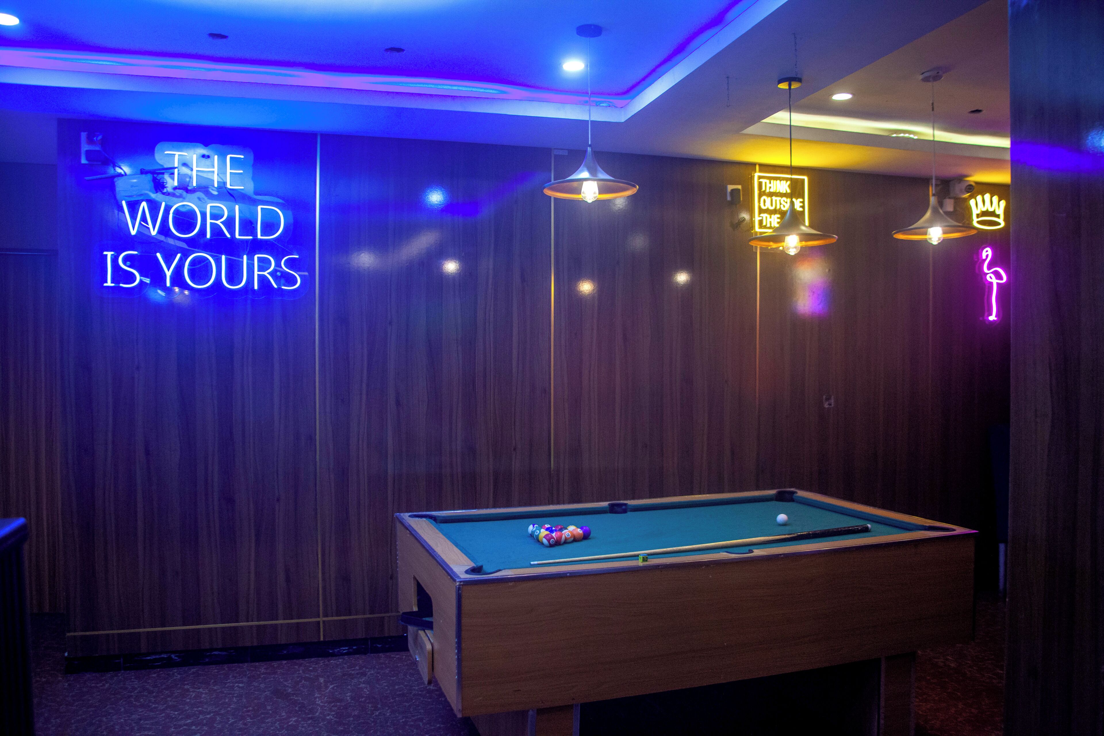 A pool table in a room with wooden paneling and neon signs.