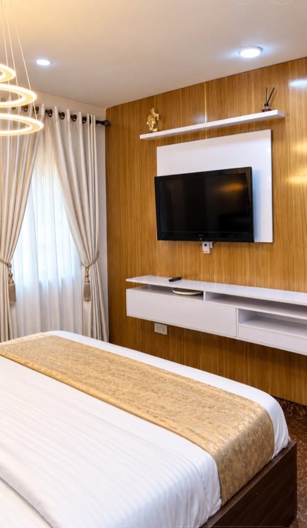 Une chambre d’hôtel avec un lit, un téléviseur fixé au mur et un panneau mural en bois.