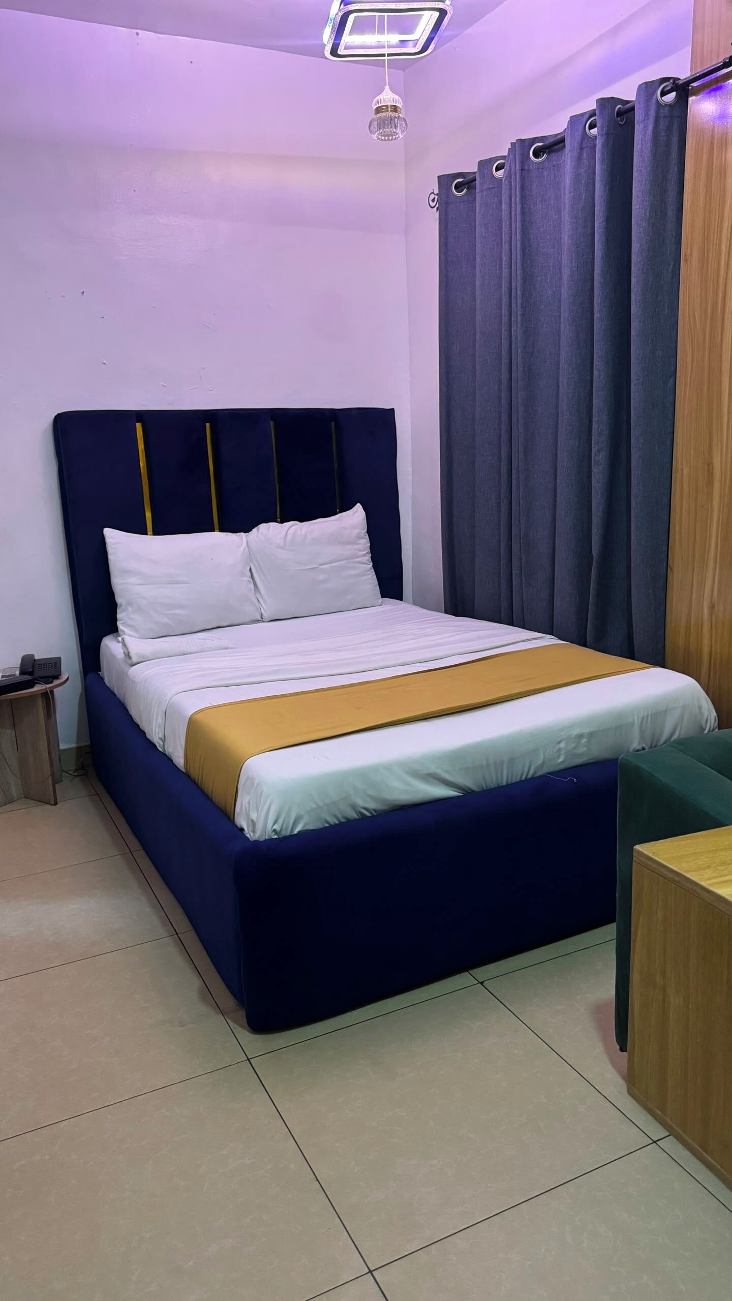 A bed with a dark headboard, white bedding, and a yellow accent.