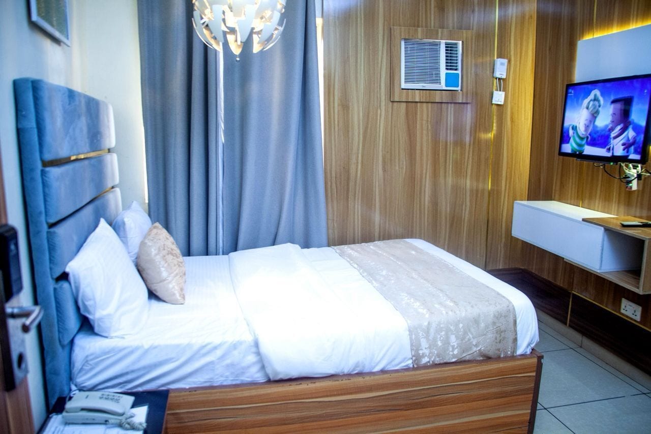 Una camera d'albergo con un letto, una televisione, una scrivania e una sedia.