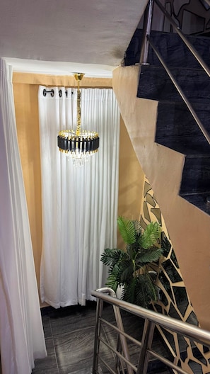 Una escalera con barandilla de metal, una cortina blanca y un candelabro.
