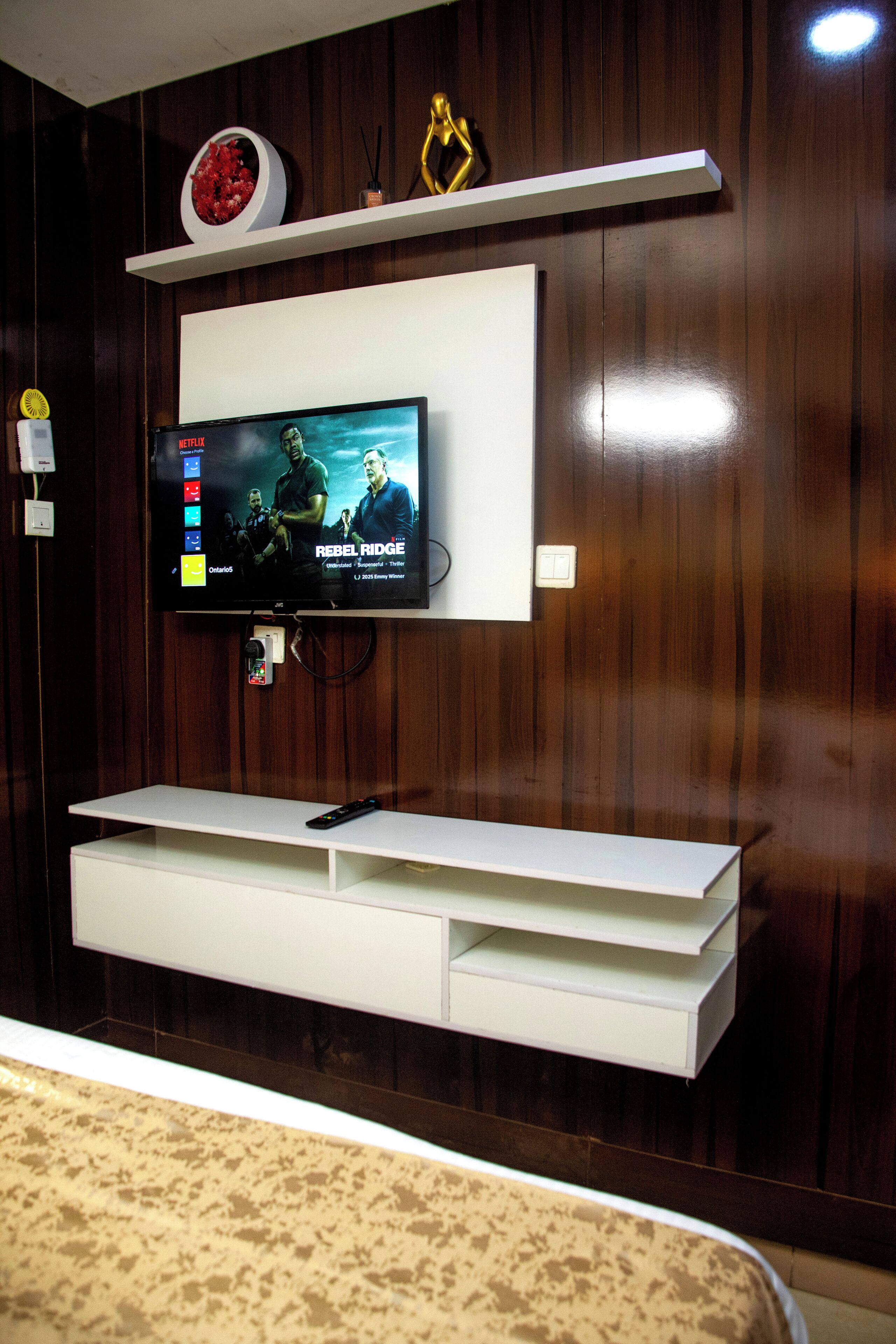 A wall-mounted TV with a white entertainment unit below it.