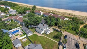 An aerial view of a residential area with houses, a swimming pool, and a beach in the background. - Beachfront 4BR - 30ft to Sand •Near Amusement Park (Keansburg)