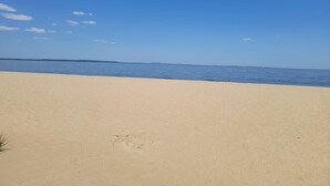 A wide sandy beach with a clear blue sky and calm sea. - Beachfront 4BR - 30ft to Sand •Near Amusement Park (Keansburg)
