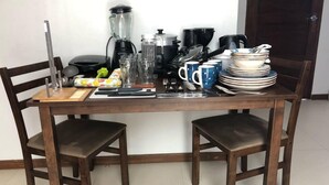 A dining table with chairs, a blender, coffee maker, and stacked plates. - 1bedstudiohuanchaco/balcony/closetolocalsights (Huanchaco)