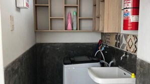 A compact kitchen with a washing machine, sink, and tiled backsplash. - 1bedstudiohuanchaco/balcony/closetolocalsights (Huanchaco)