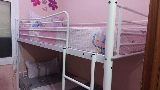 Ein Stockbett mit einer rosa Wand und floralen Verzierungen.