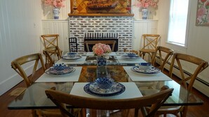 Une salle à manger avec une table en verre, des chaises en bois et de la vaisselle bleue et blanche à motifs.