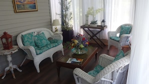 Un salon chaleureux avec des meubles en osier, un tableau accroché au mur et une plante en pot.