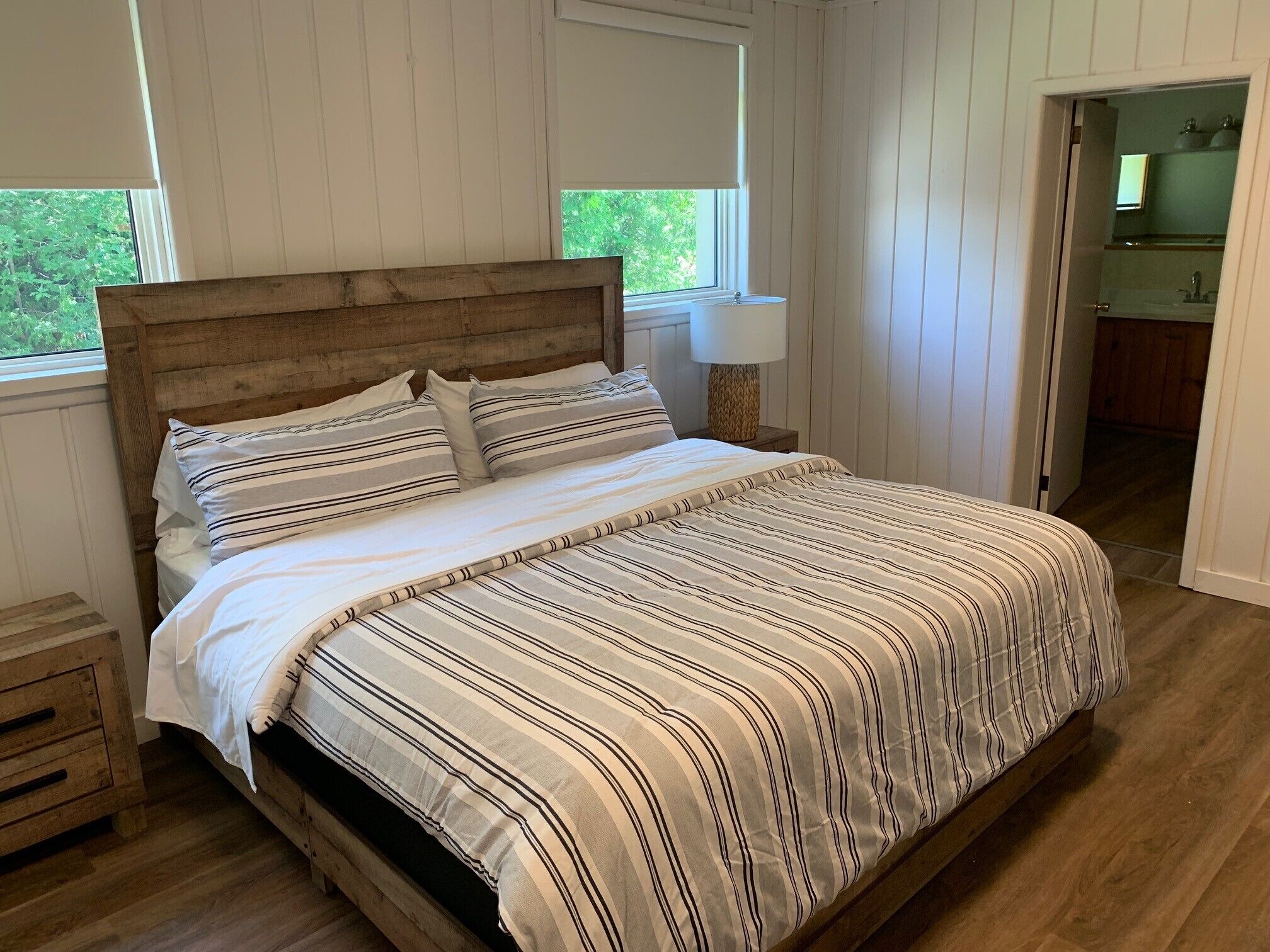 Une chambre à coucher avec une tête de lit en bois, une couvre-lit à rayures et une table de chevet avec une lampe.