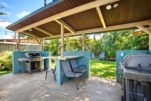 Eine Außenpatio mit Grillstation, zwei Stühlen und einem Betonboden.