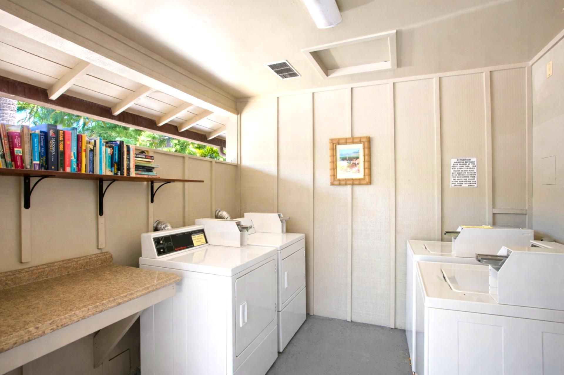 A laundry room with a washing machine, dryer, and a shelf with books.