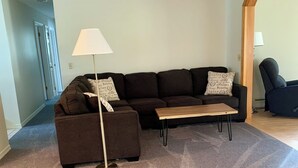 Ein Wohnzimmer mit einem dunkelbraunen Sofa, einem Holztisch und einer Stehlampe.