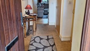 En hall med ett mönstrat mattgolv som leder in till ett vardagsrum med en soffa och en lampa.