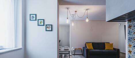 A modern living room with a black sofa, yellow cushions, and a dining area with a table and chairs.