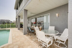 En overdækket terrasse med pool, udendørs møbler og en glasdør, der fører til en overdækket gang.